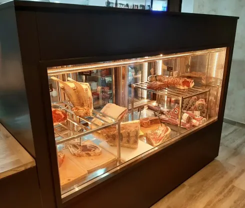 Vitrina que muestra diversos cortes de carne cruda, iluminada por luces cenital.