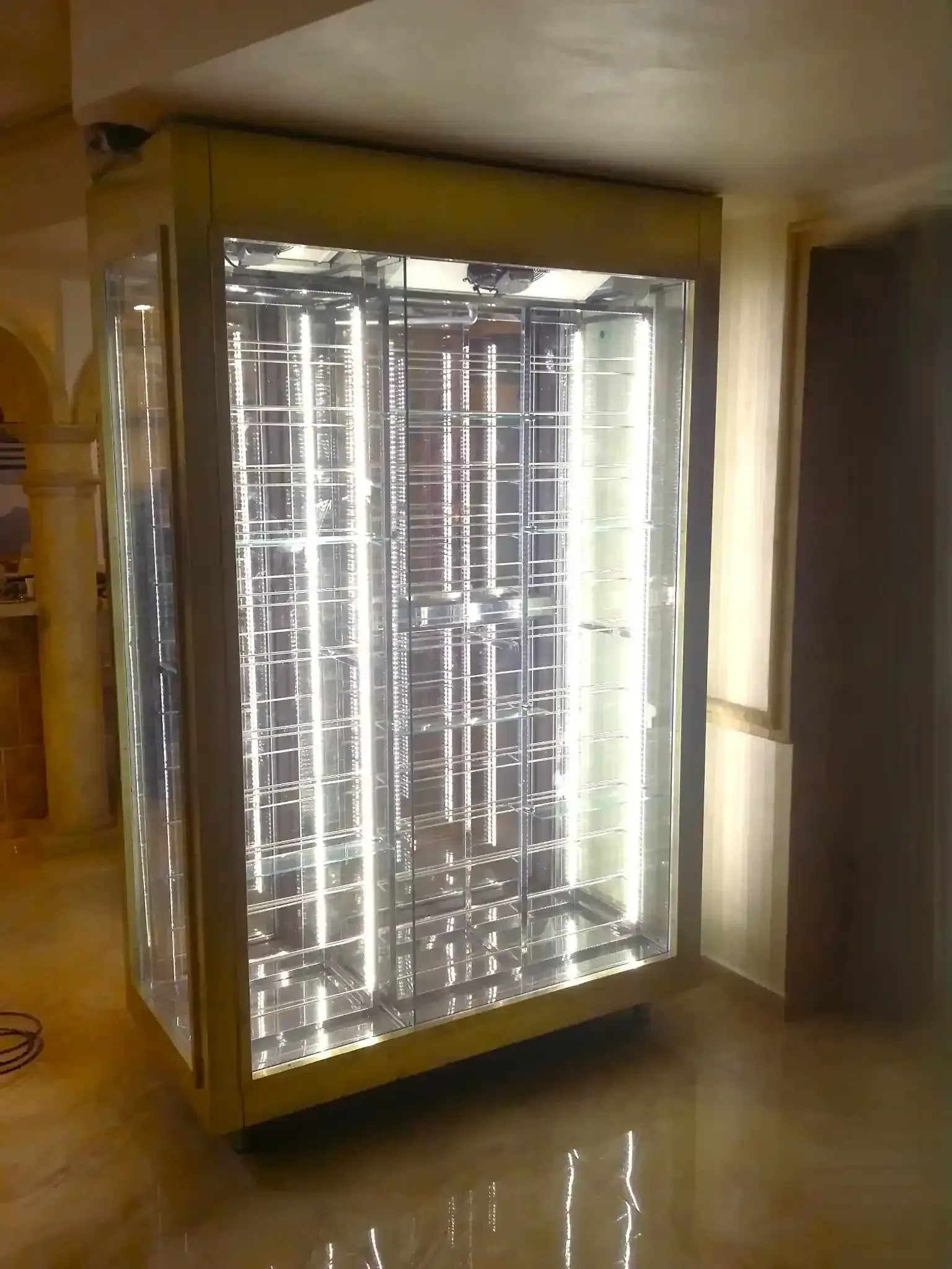 Cabina de bronceado con iluminación interior brillante. Marco amarillo, paneles de vidrio y rejilla metálica reflectante.