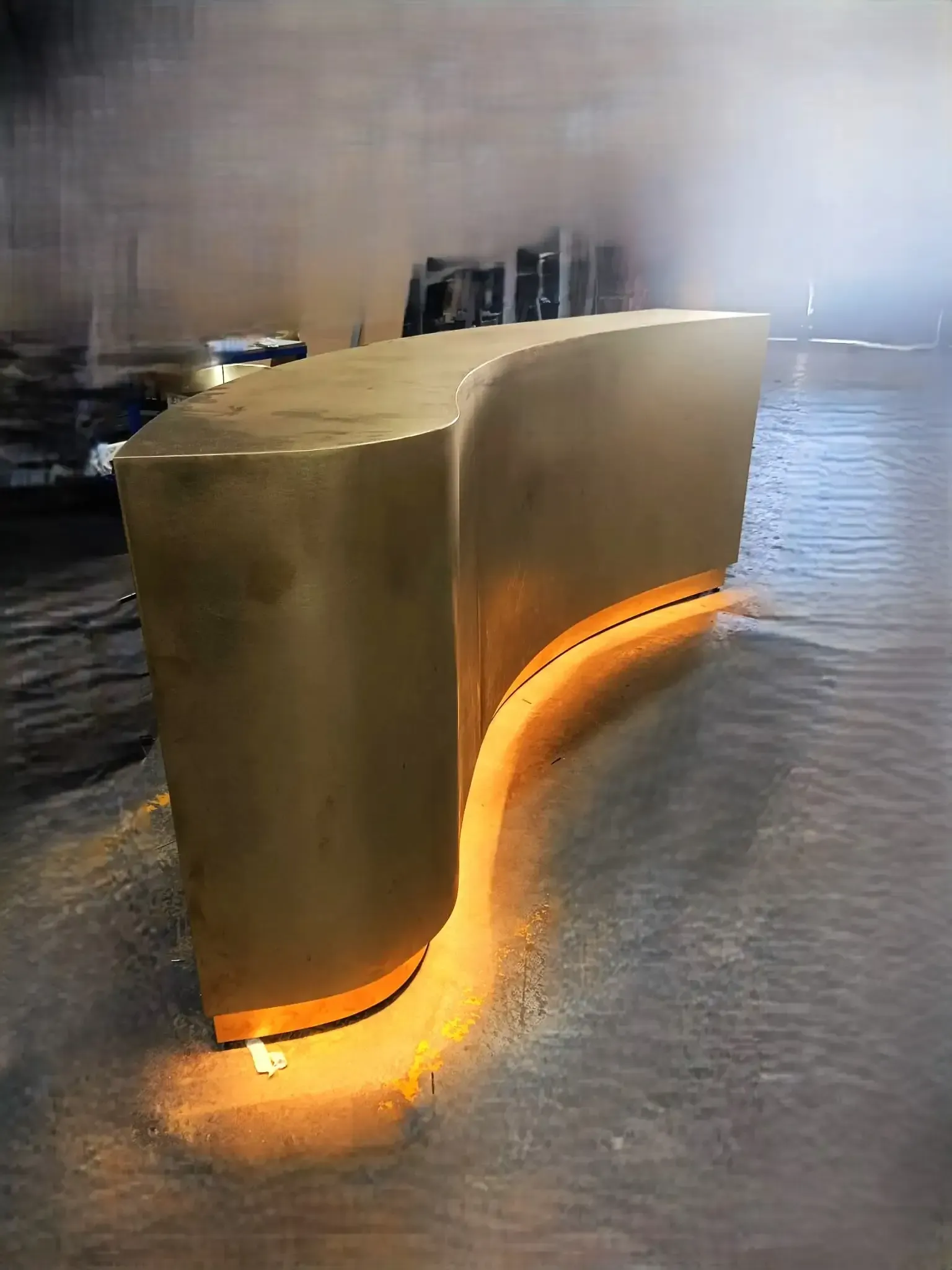 Banco dorado y curvo con resplandor naranja, en aguas poco profundas, que refleja la luz.