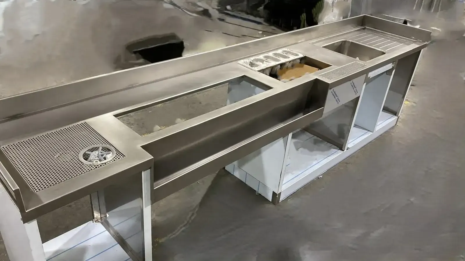Estación de trabajo de barra de acero inoxidable con fregaderos incorporados, depósitos de hielo y estantes