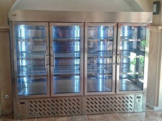 Vitrina refrigerada de gran tamaño en acero inoxidable con cuatro puertas y estantes de cristal.