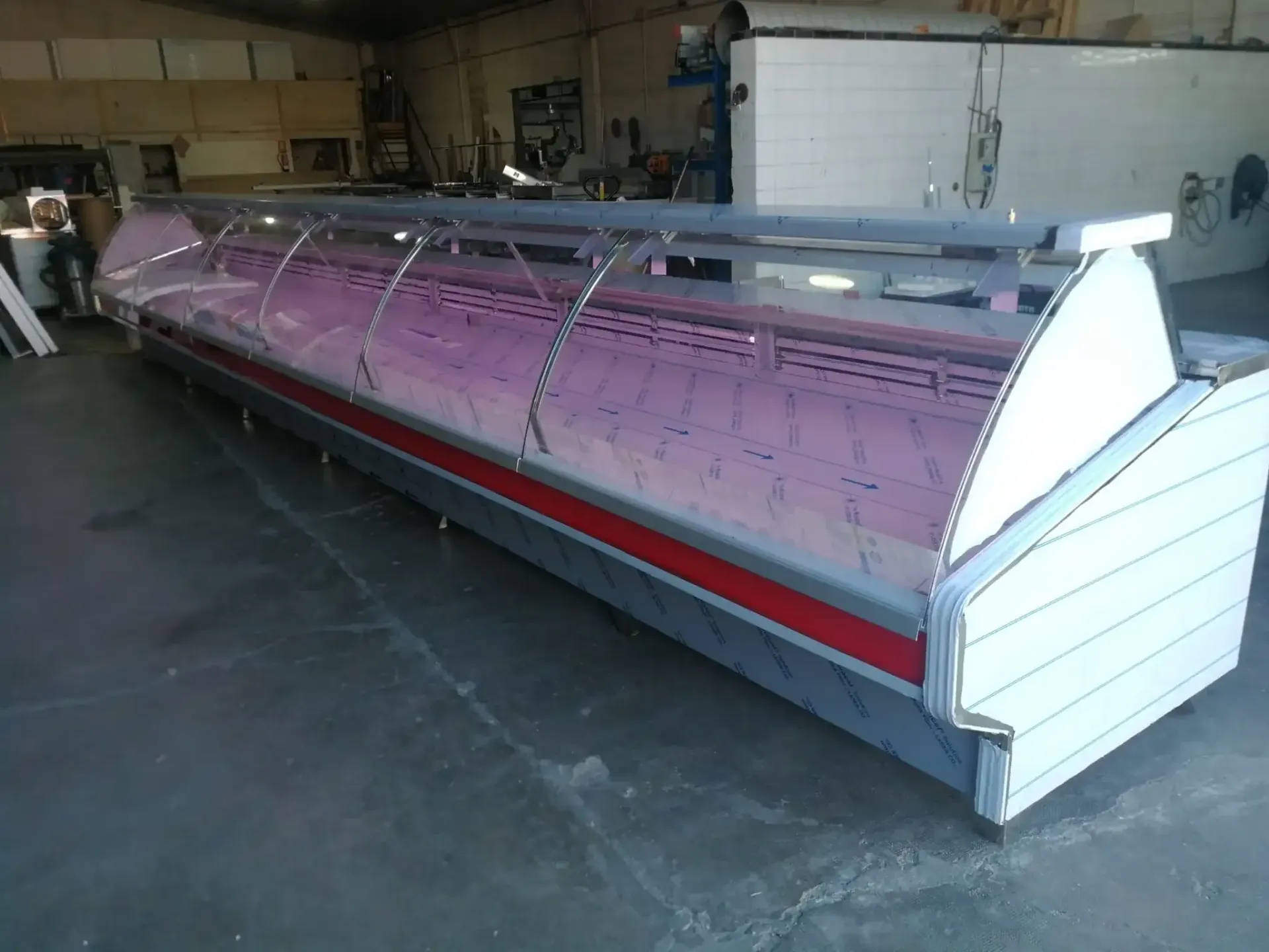 Vitrina refrigerada comercial de gran tamaño, de color blanco, rojo y plata, en entorno industrial.