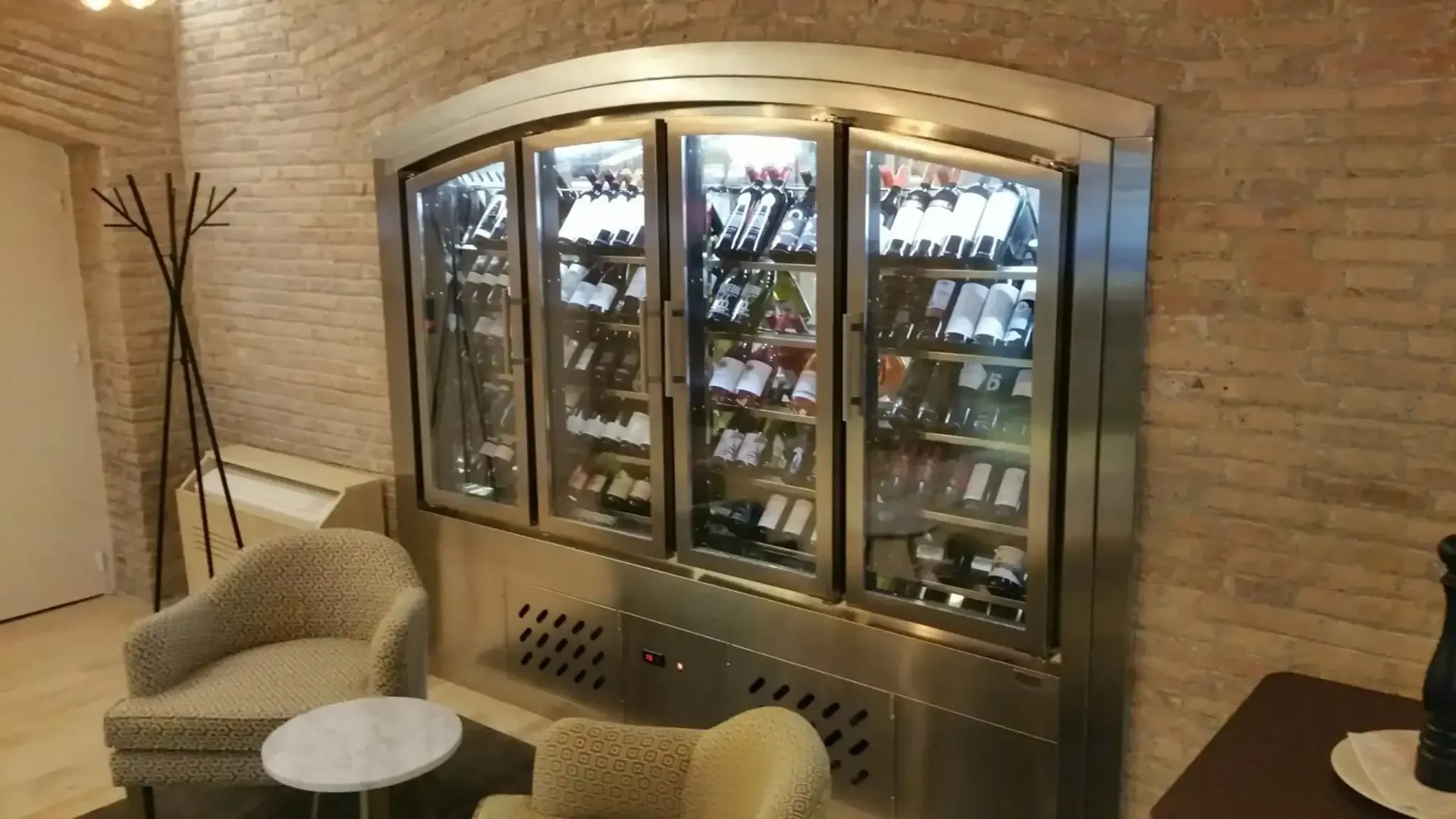 Bodega con vitrina de acero inoxidable, pared de ladrillo y zona de estar.