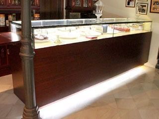 Vitrina con interior iluminado, que muestra joyas contra un mueble de madera oscura.