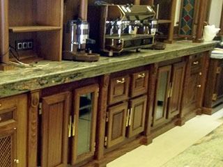 Barra de madera con máquinas de café expreso y muebles, encimera verde.