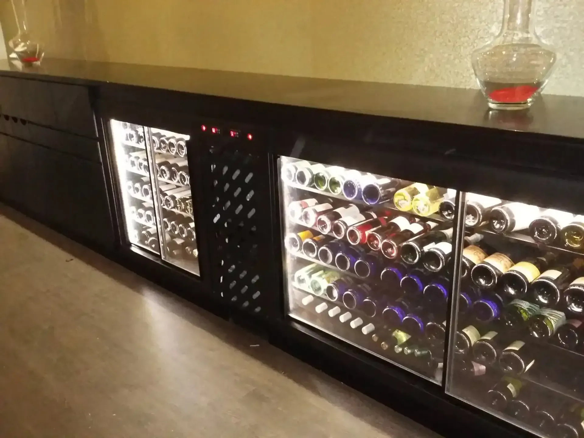 Armario para vinos de color negro con botellas iluminadas.