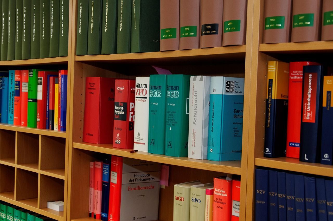 Livros em prateleiras de madeira, cores variadas, ambiente de biblioteca.