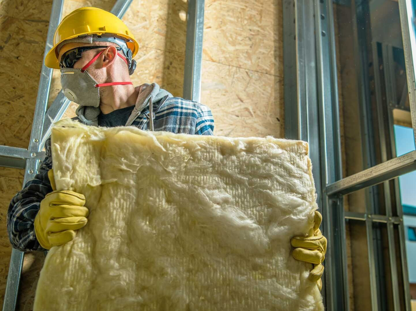 Artisan avec masque qui tient une plaque en laine de roche