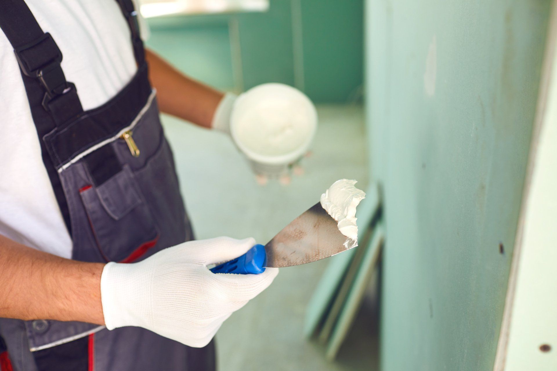 Artisan qui tient un couteau à enduire avec du plâtre