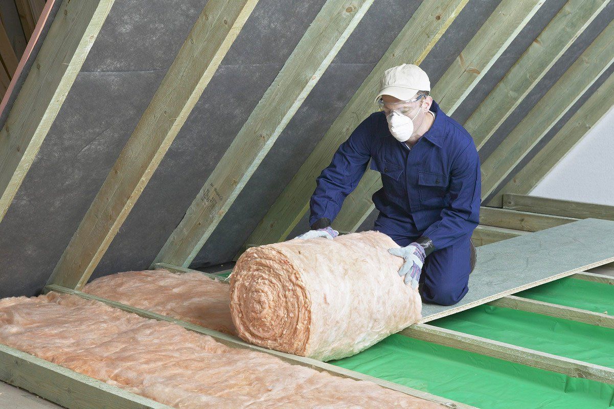 Artisan qui pose de la mousse isolante dans des combles