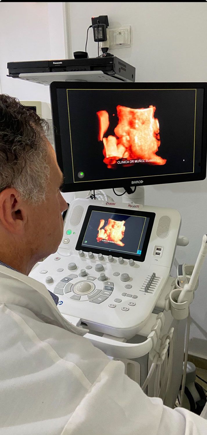 Una persona mira una máquina de ultrasonido que muestra una imagen tridimensional de color naranja de un feto, probablemente en un entorno médico.