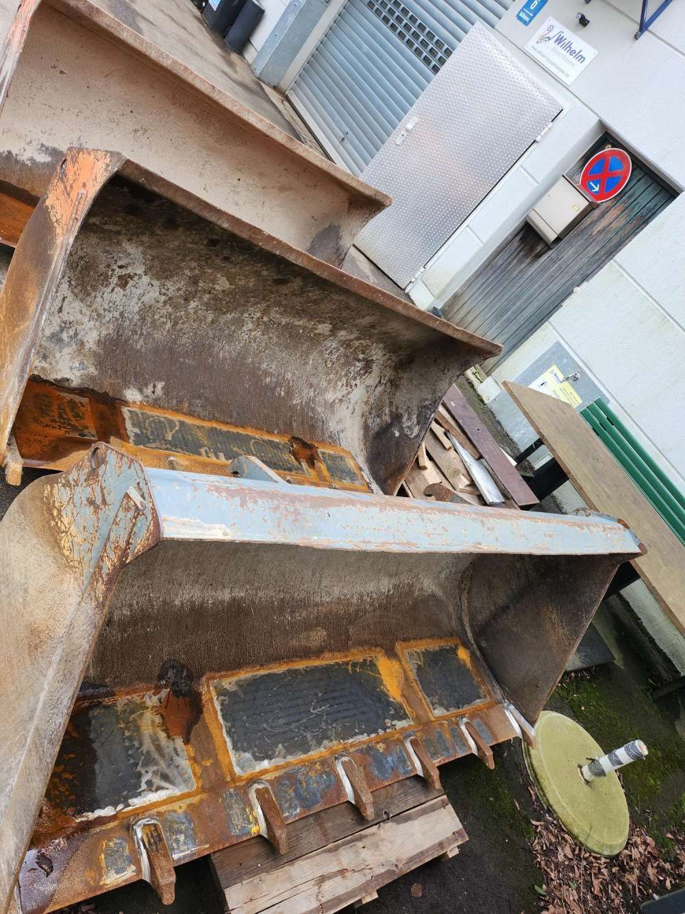 Ein rostiger Metallcontainer oder Abfallbehälter neben einem Gebäude auf dem Bürgersteig im Freien