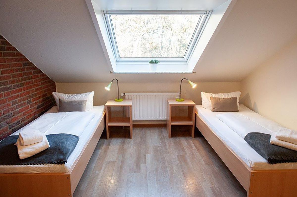 Kleines Dachgeschosszimmer mit zwei Einzelbetten, Dachfenster und Nachttischen