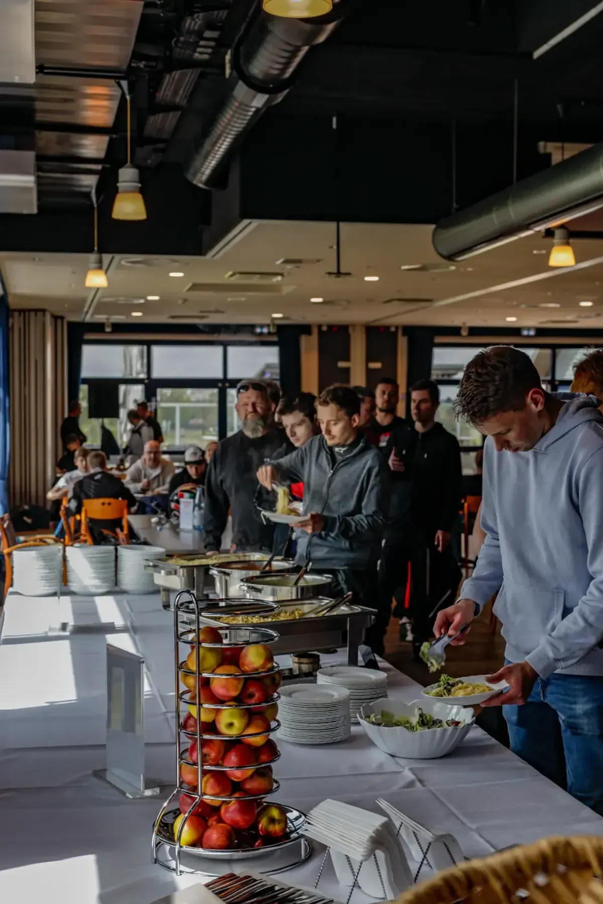 In einem modernen Büro versammelten sich Menschen an einem Buffet, im Vordergrund war eine hohe Obstauslage zu sehen.