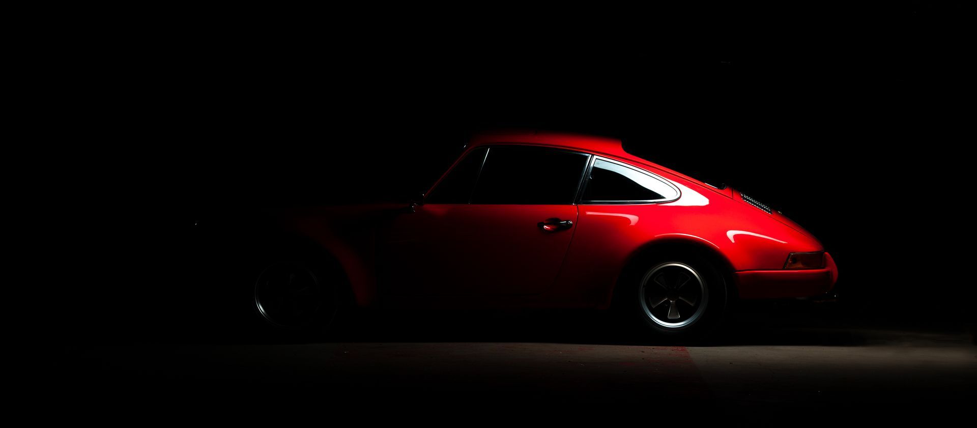 One Car AG - Roter Porsche von einzelnem Licht beleuchtet im Dunkeln