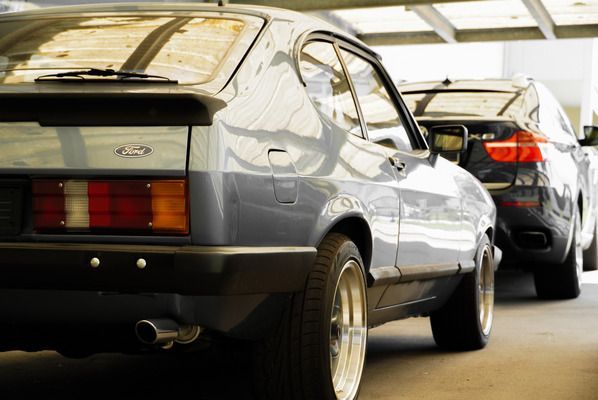 One Car AG - Modernes und altes Auto stehen hintereinander in einer Halle