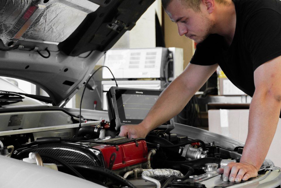 One Car AG - Mechaniker beugt sich über einen Automotor