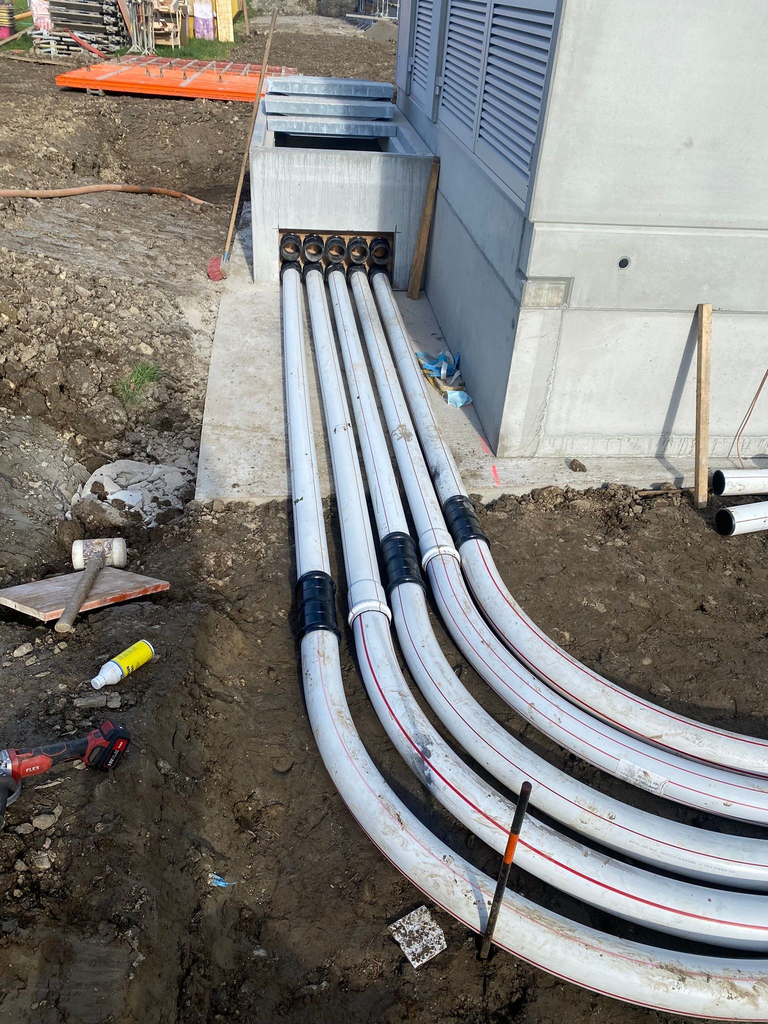 Vor einem Gebäude liegen mehrere Rohre im Dreck.