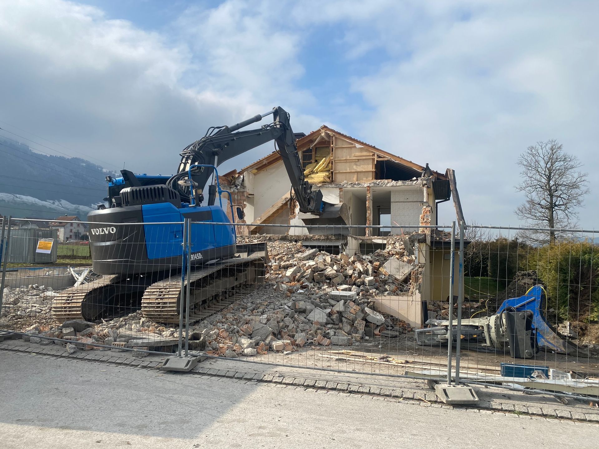 Ein großer blauer Bagger zerstört ein Haus.