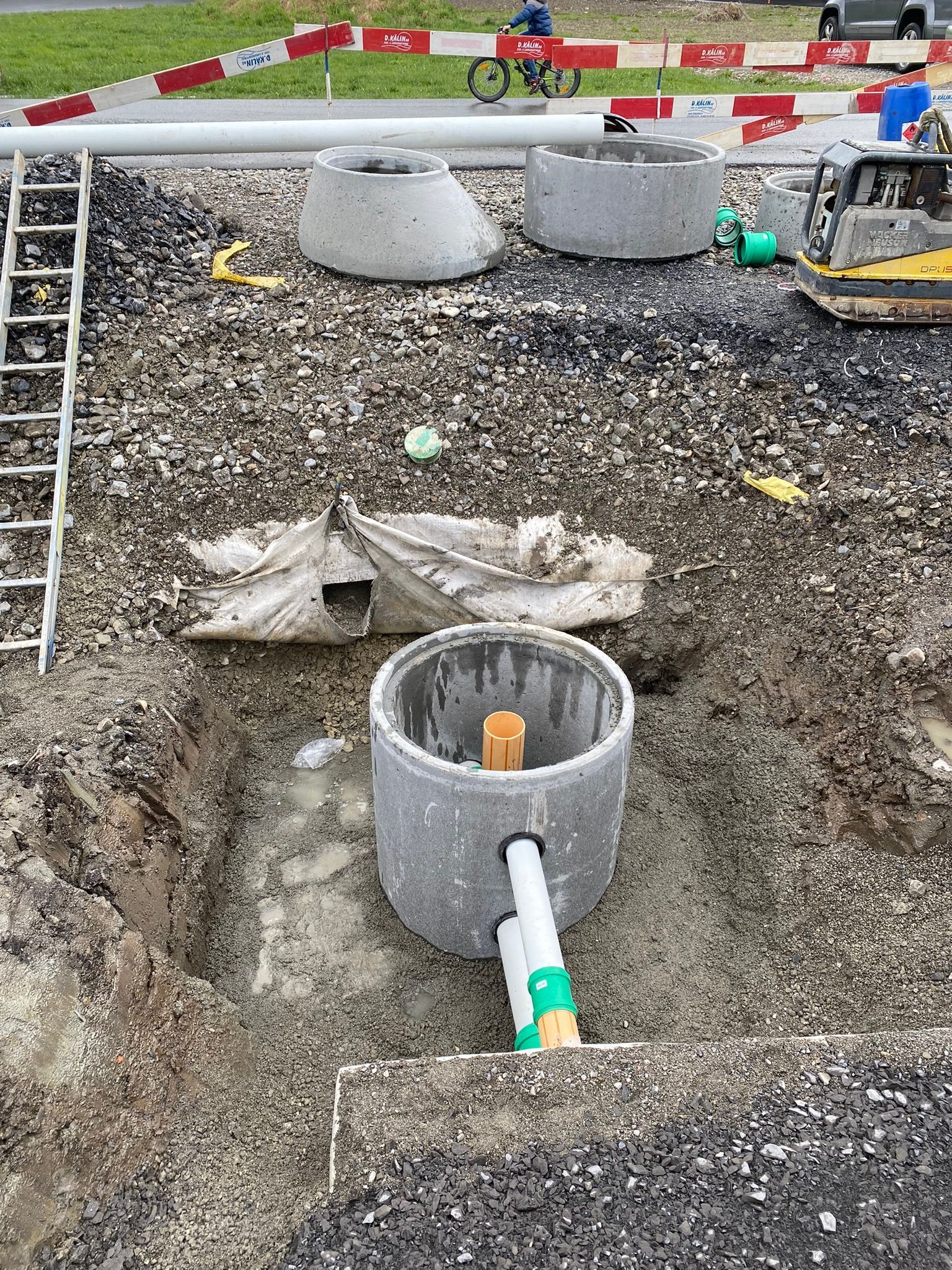 In einem Loch im Boden wird ein Schachtdeckel installiert.