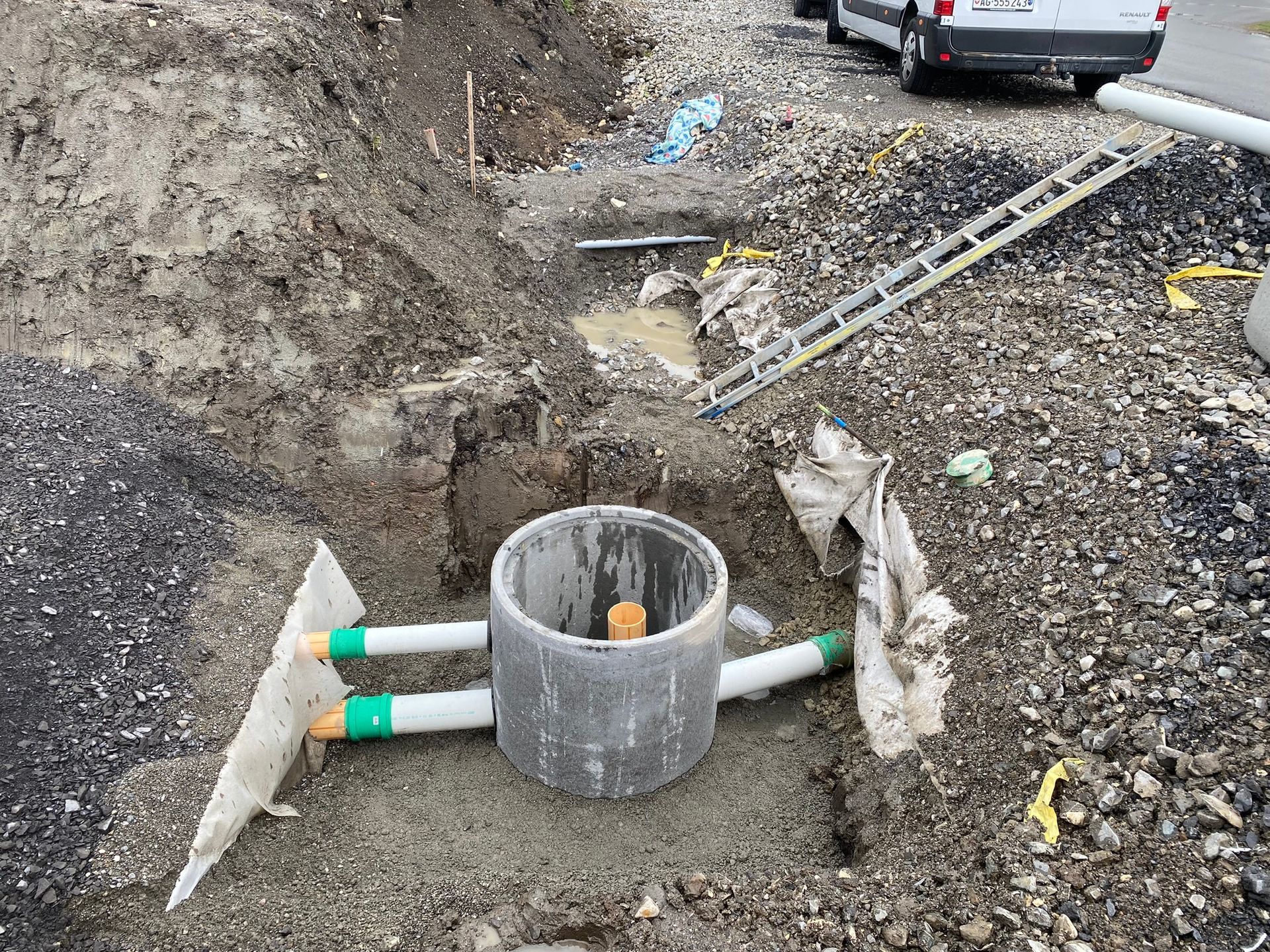 In einem Loch im Boden wird ein Schachtdeckel installiert.