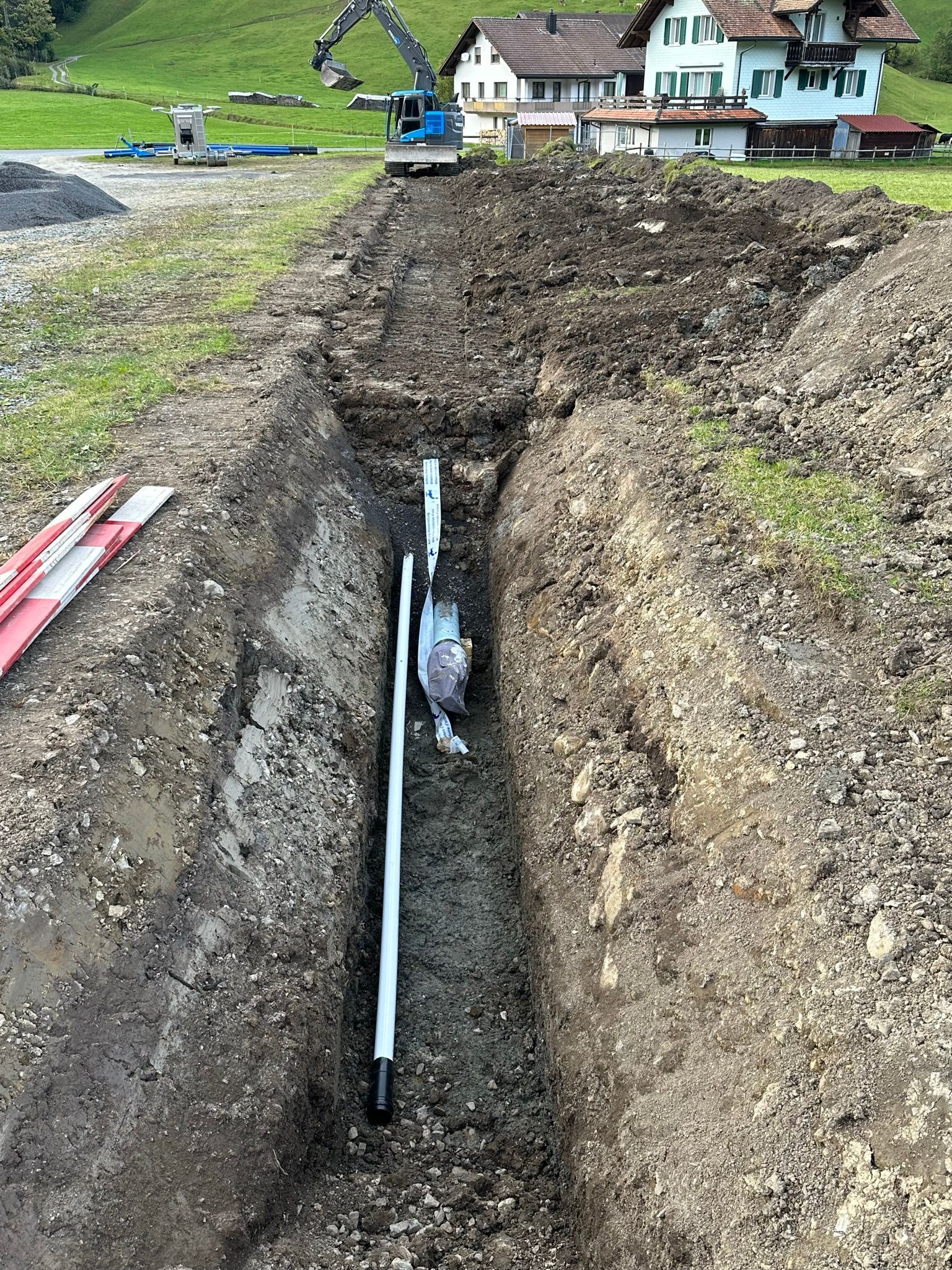 In einem Loch im Boden wird ein Rohr installiert.