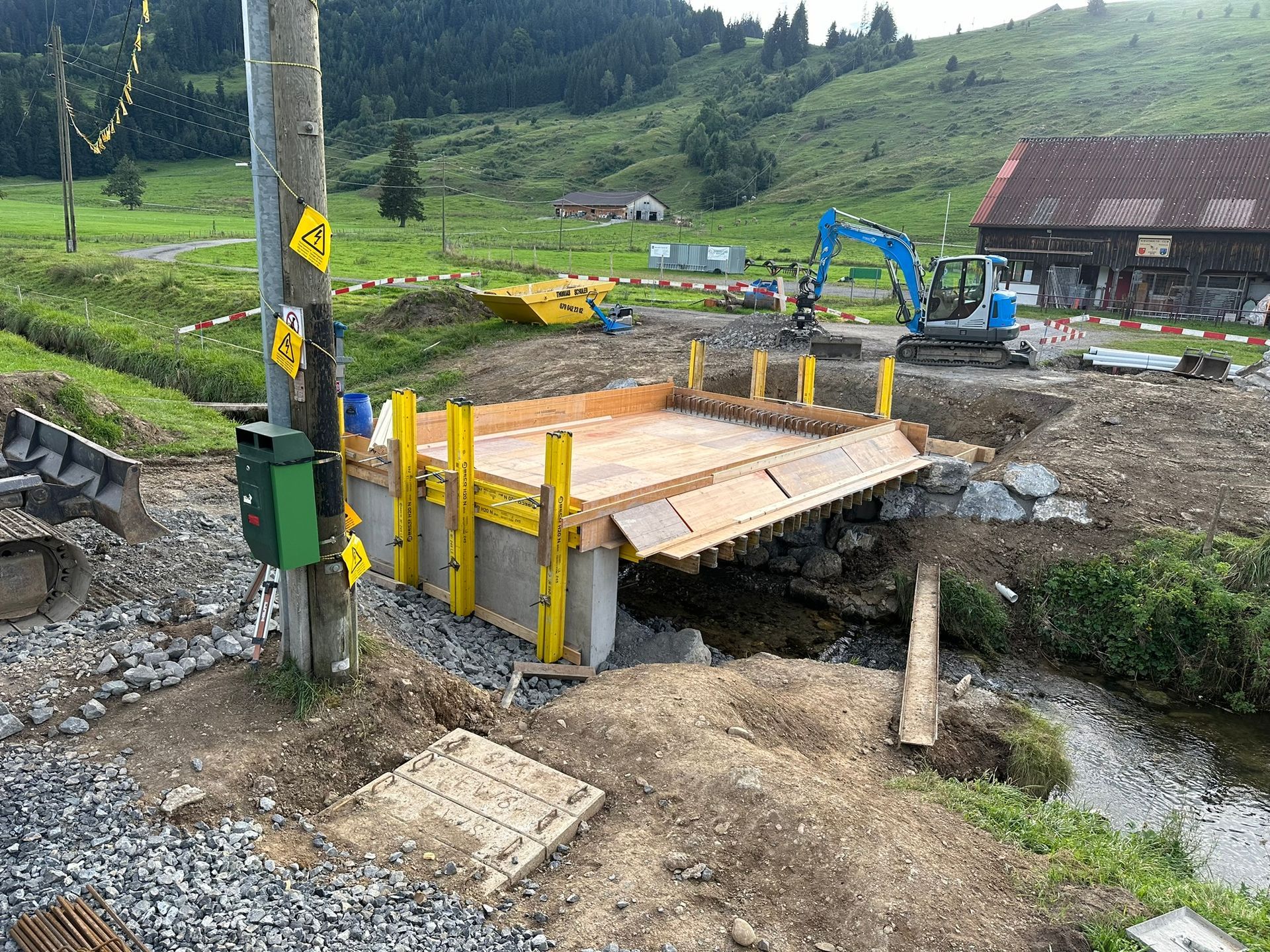 Über einen Bach auf einem Feld wird eine Brücke gebaut.