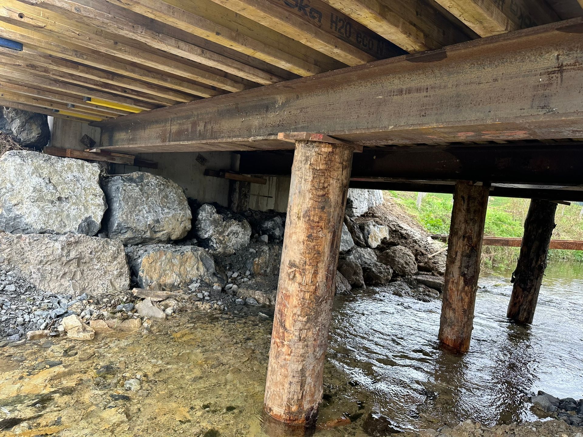 Die Unterseite einer Holzbrücke über ein Gewässer.