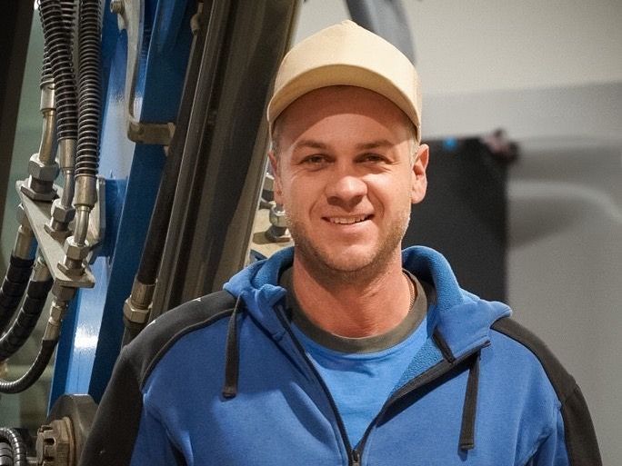 Ein blauer Bagger gräbt auf einer Baustelle ein Loch. Foto von der ST-Bau AG