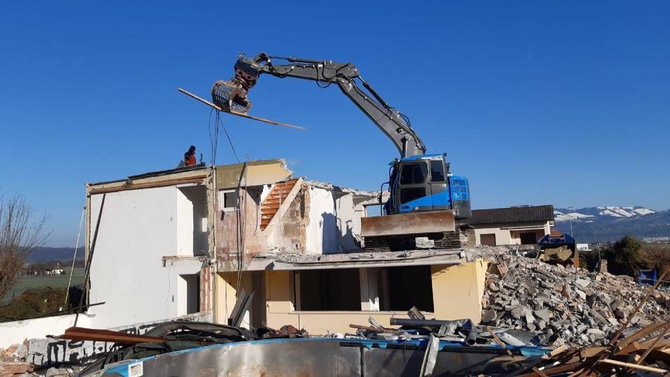 Ein großes Gebäude wird mit einem Kran abgerissen.