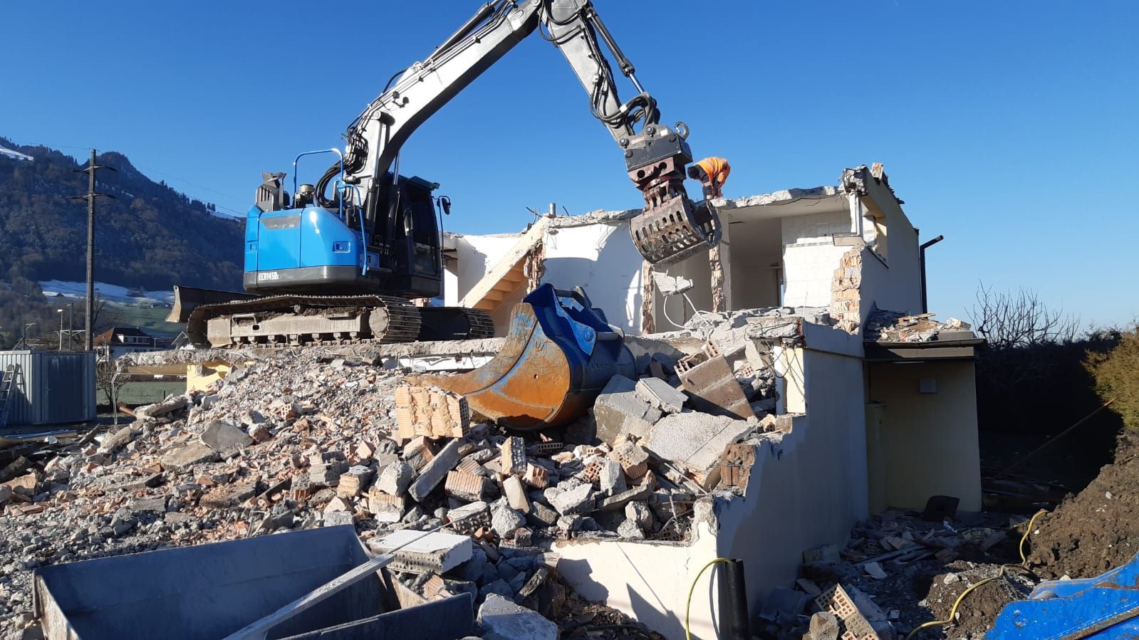 Ein großer Bagger zerstört auf einer Baustelle ein Gebäude.