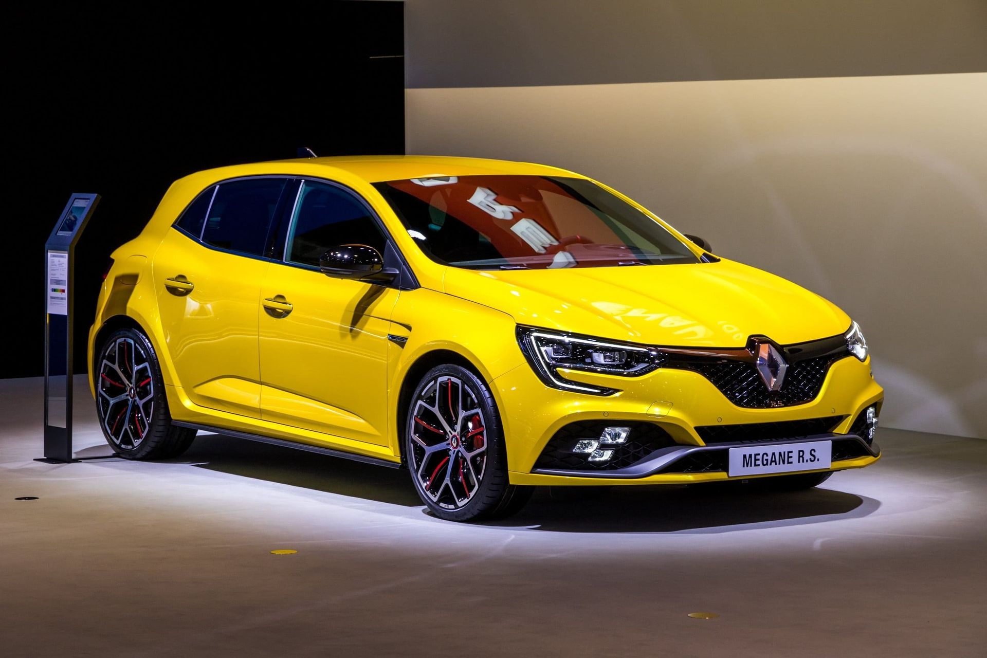 Renault Mégane RS amarillo estacionado en una sala de exposición, llantas negras y detalles en rojo.