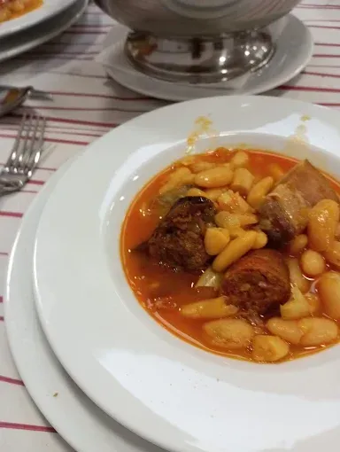 Un tazón de sopa con frijoles y carne en una mesa.