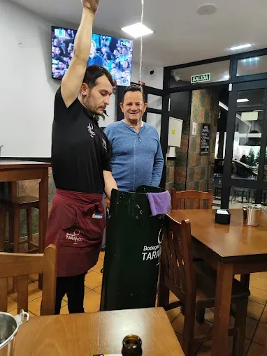 Dos hombres están de pie en un restaurante sosteniendo una bolsa verde.
