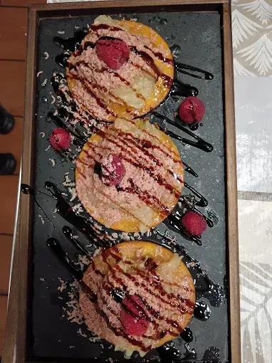 Una bandeja de postres con frambuesas y salsa de chocolate sobre una mesa.