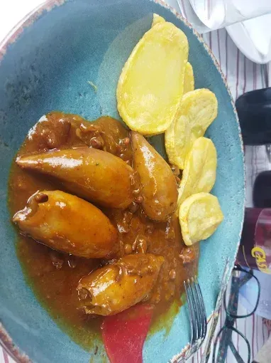 Un plato de comida con salsa y patatas sobre una mesa.