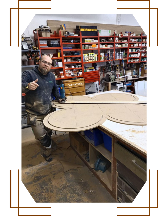 Un hombre está de pie junto a un gran trozo de madera en un taller.