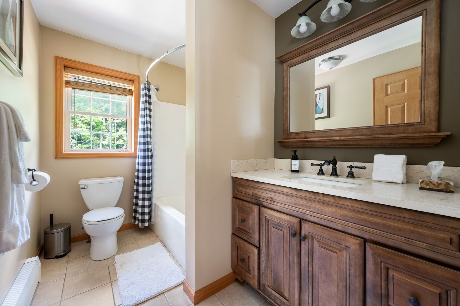 Bathroom with wooden vanity, large mirror, toilet, and shower curtain.