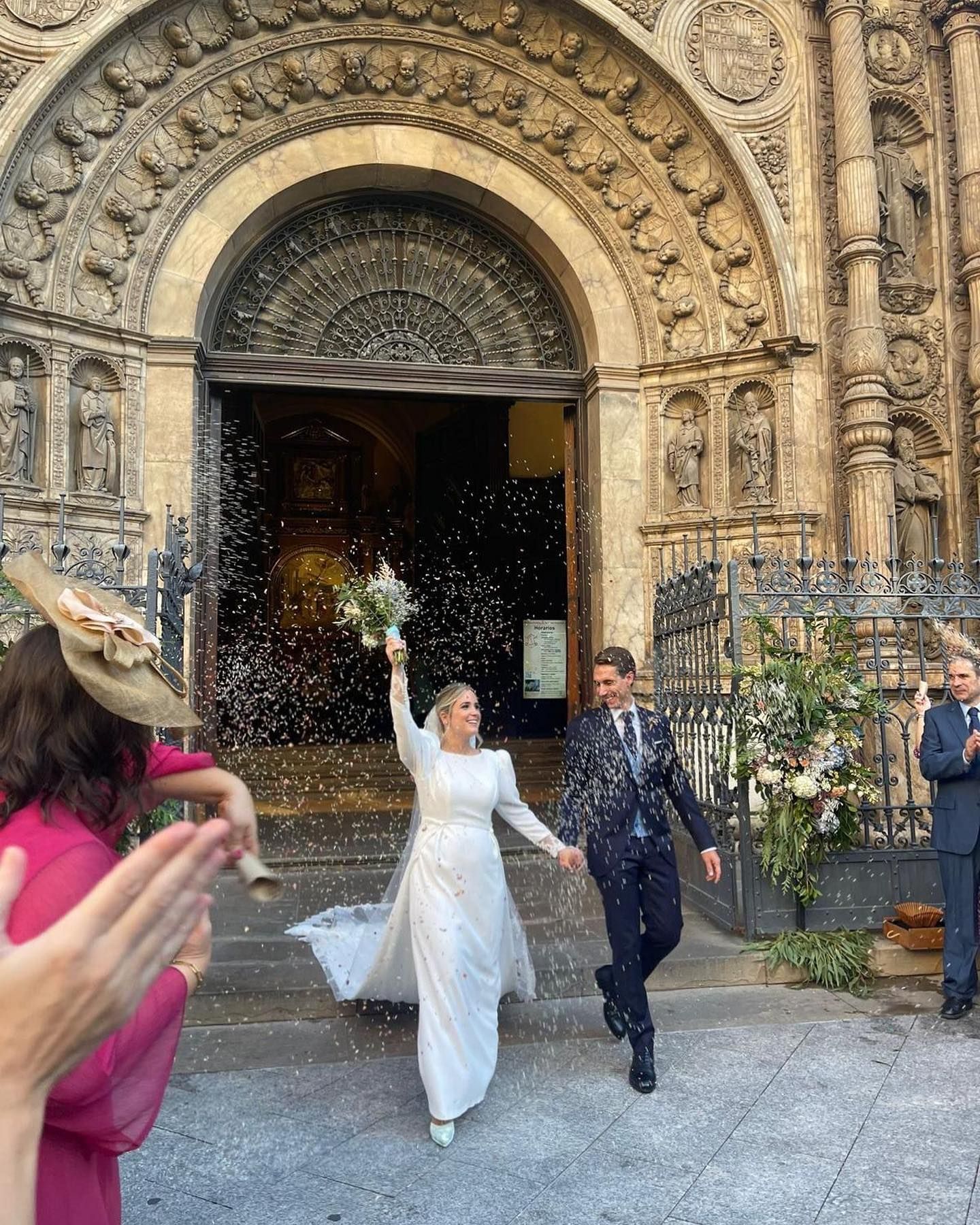 Una novia y un novio salen de una iglesia tomados de la mano.