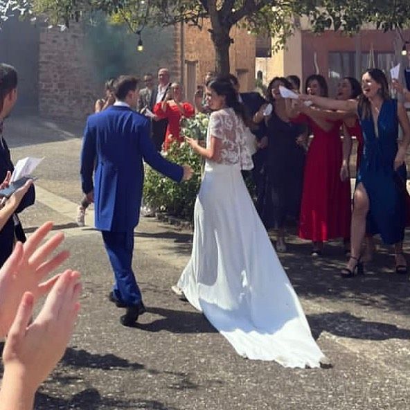 Una novia y un novio están bailando delante de una multitud de personas.
