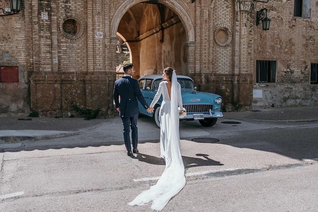 Una novia y un novio caminan por la calle tomados de la mano.