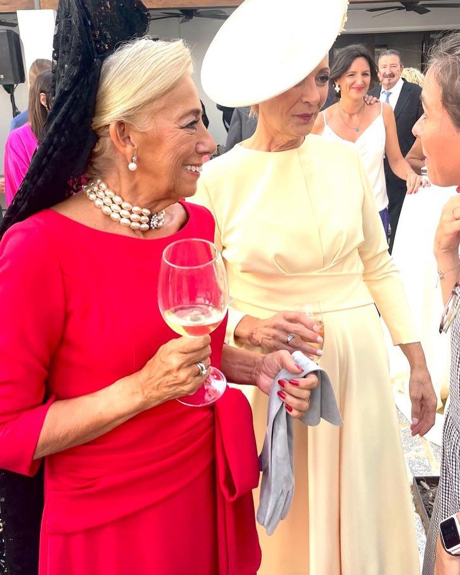 Dos mujeres están paradas una al lado de la otra sosteniendo copas de vino.