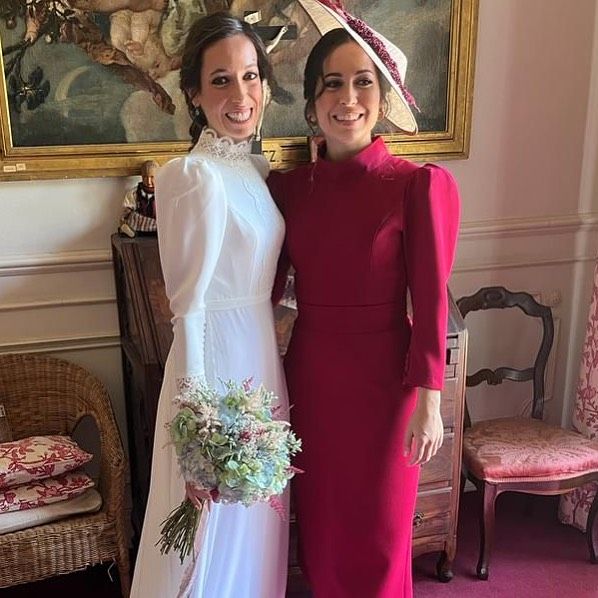 Una novia y su doncella posan para una fotografía en una habitación.