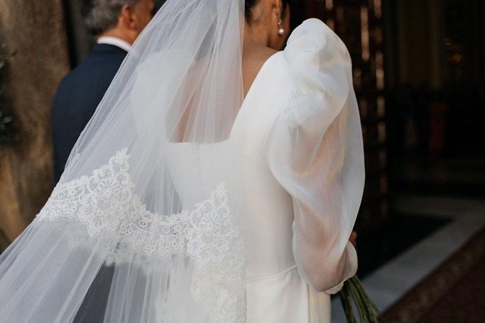 Una novia con un vestido blanco y velo camina hacia el altar.