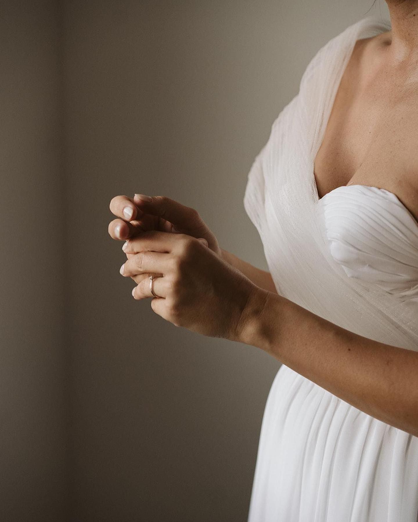 Una mujer con un vestido blanco sostiene sus manos juntas.