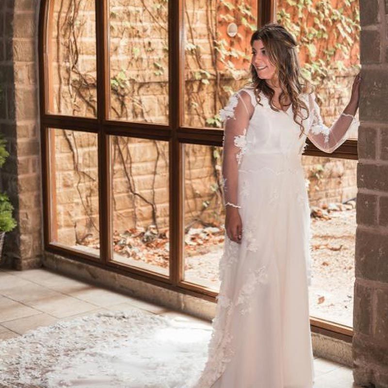 Una mujer con un vestido de novia está parada frente a una ventana.