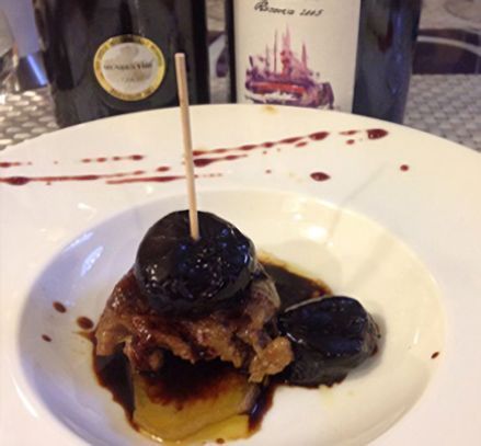 Un plato de comida con una botella de vino al fondo.