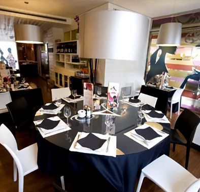 Una mesa redonda con un mantel negro y sillas blancas.