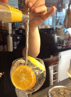 Una persona está vertiendo una bebida en un vaso con rodajas de limón.