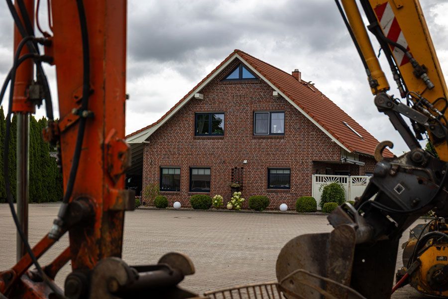Backsteinhaus, gesehen durch Baumaschinen unter einem bewölkten Himmel